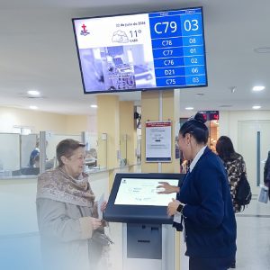 Asistente ayudando a una paciente mayor a realizar su admisión en el totem digital